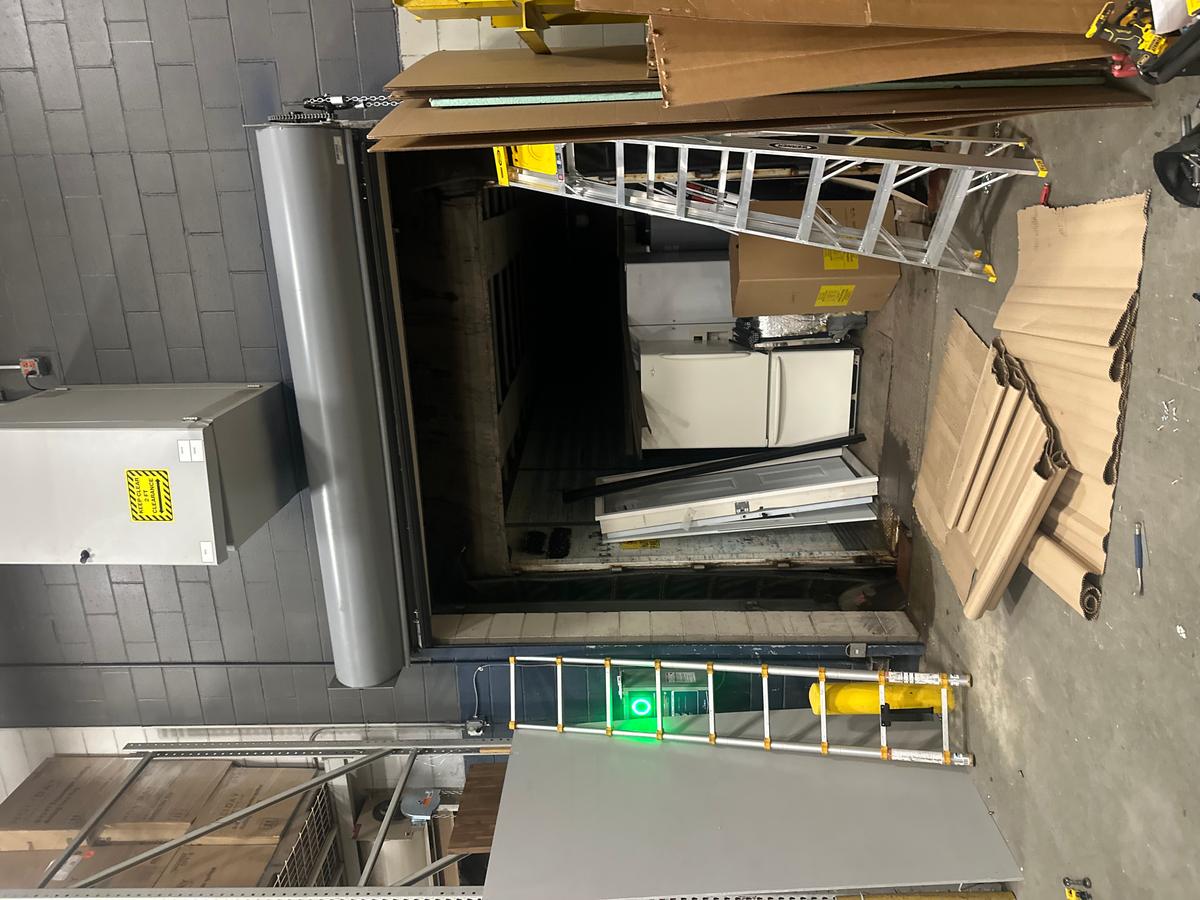 Commercial loading-bay door opening with nearby ladder and staging materials